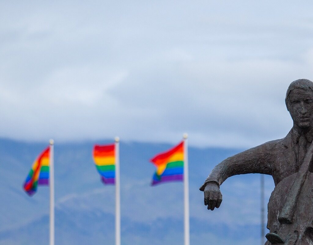 statue playing instrument in front of LGBT flags