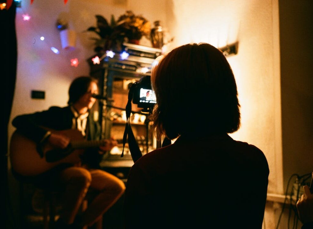 Woman recording a guitar player for a music video.
