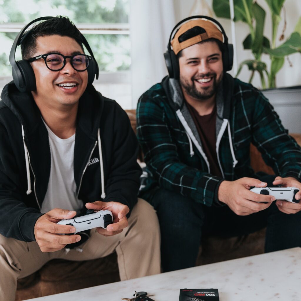 two men playing side by side holding XBOX controllers.