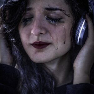 Woman crying while holding headphones