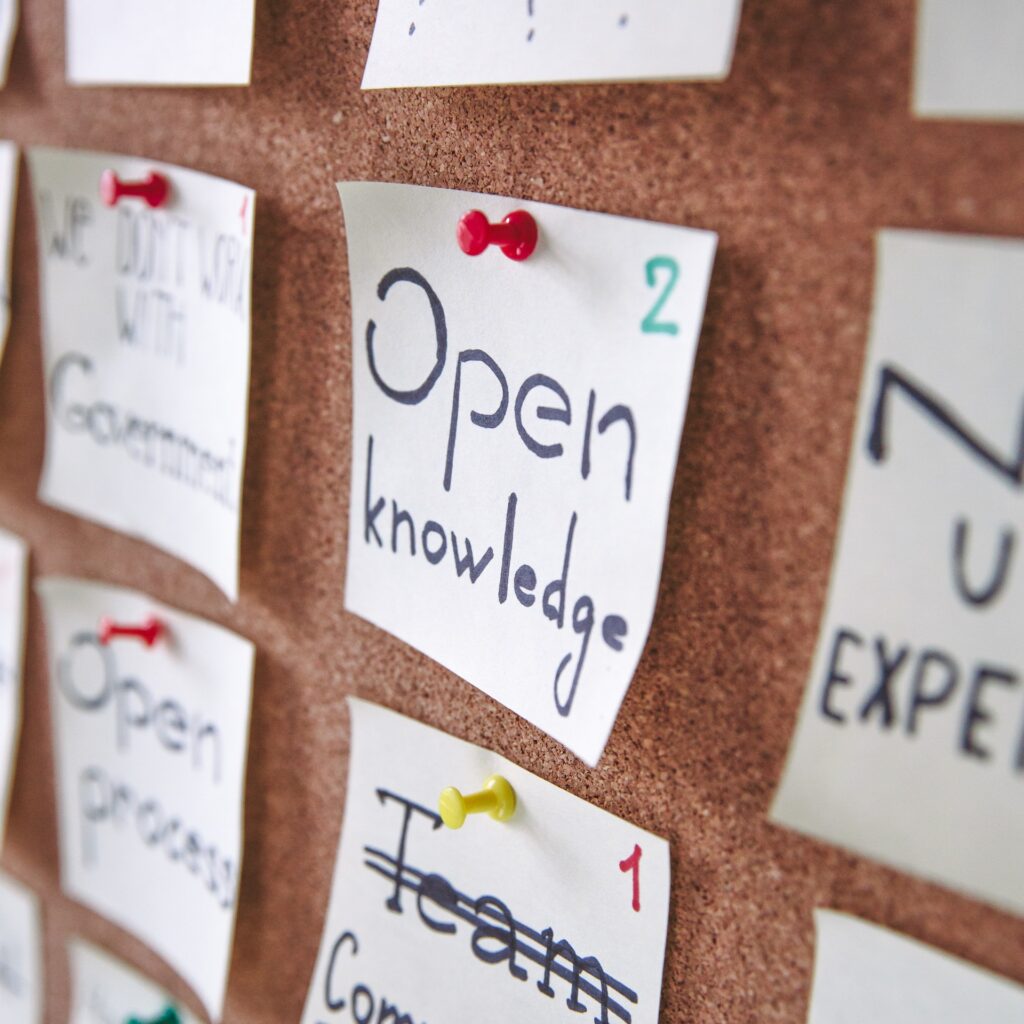 Bulletin board with white index cards spelling out open knowledge, and community.