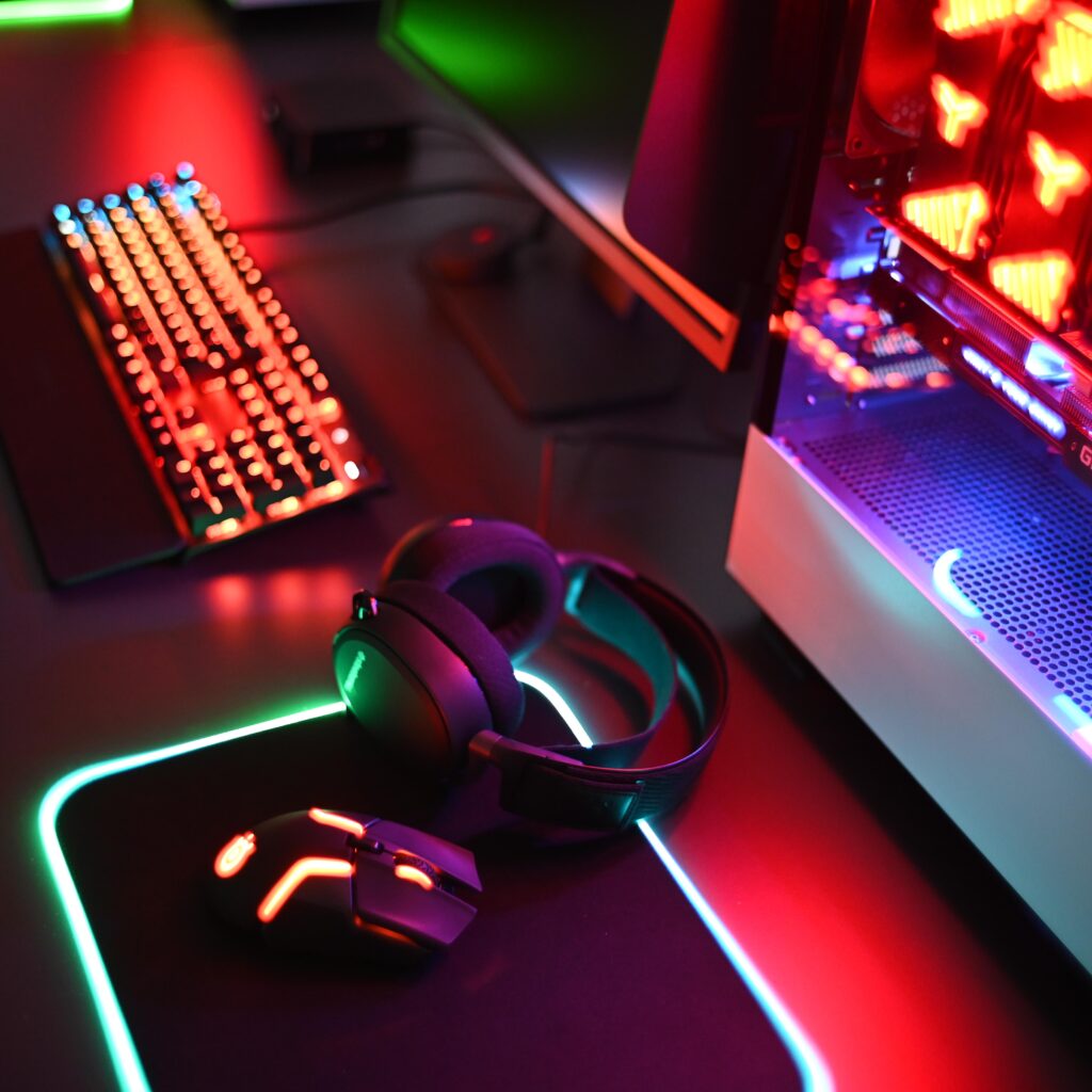 A colorfully lit PC setup on a desk with a keyboard, mousepad, mouse, and headset. 