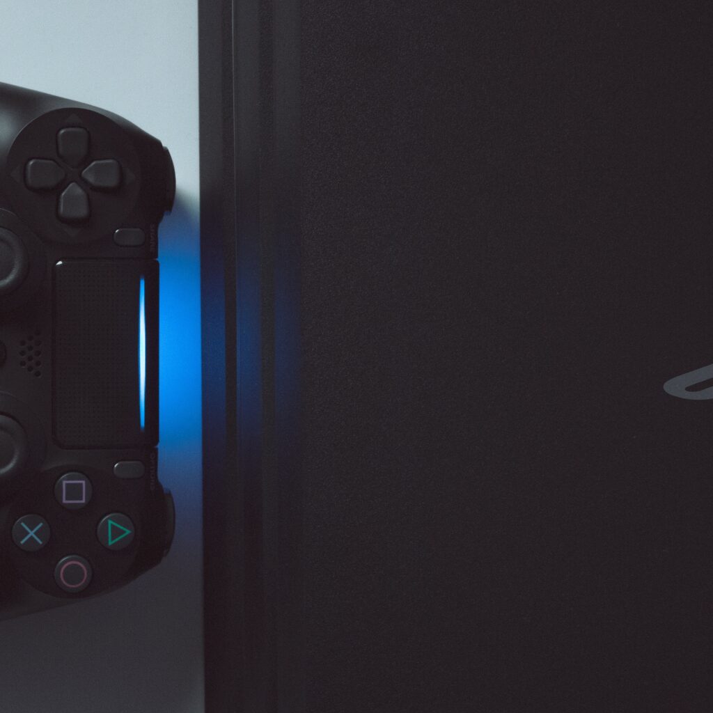 A PS4 and lit PS4 controller side by side. 