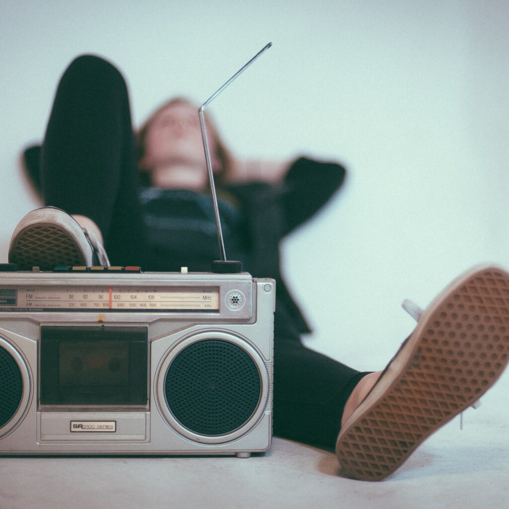 Stand alone radio on the ground while a person lays behind it to represent music's role in grief.
