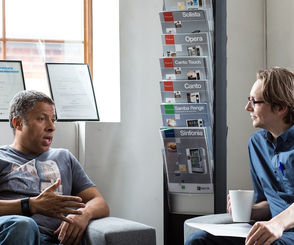 Two men sitting across from each other and talking. 