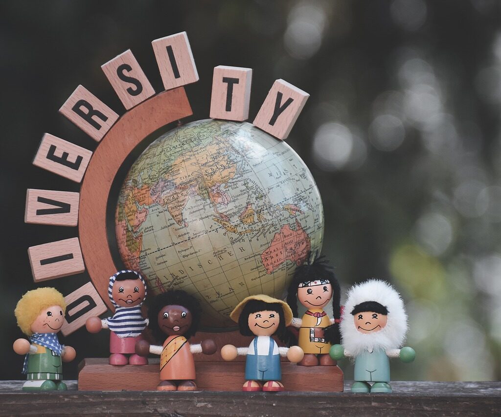 A globe with the word diversity on top and wooden figures that represent different cultures.