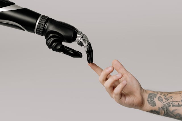 Image of human hand index finger touching artificial intelligence robot index finger.