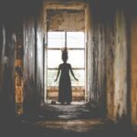 Girl standing in front of window with hair standing up. In an article talking about horror games for PC player.