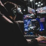 Man playing video game at computer with headset.