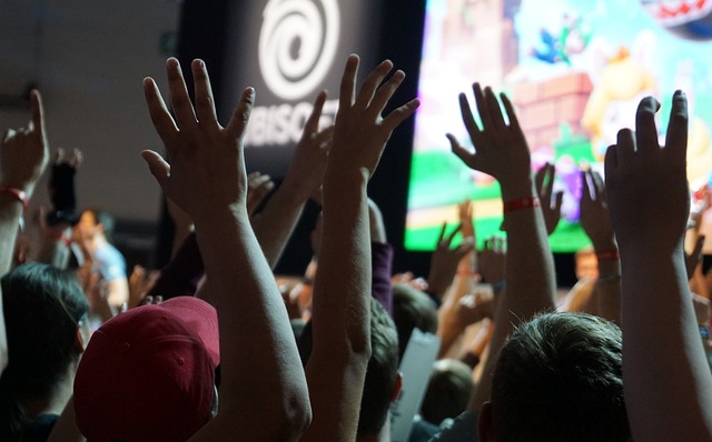 People with hands in air at Gamescom convention.