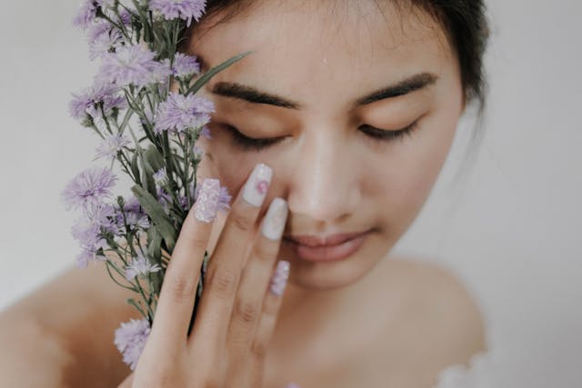 Woman holding flowers next to face with floral decorated nail