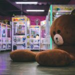 Teddy bear in arcade with games inside, including rhythm games.