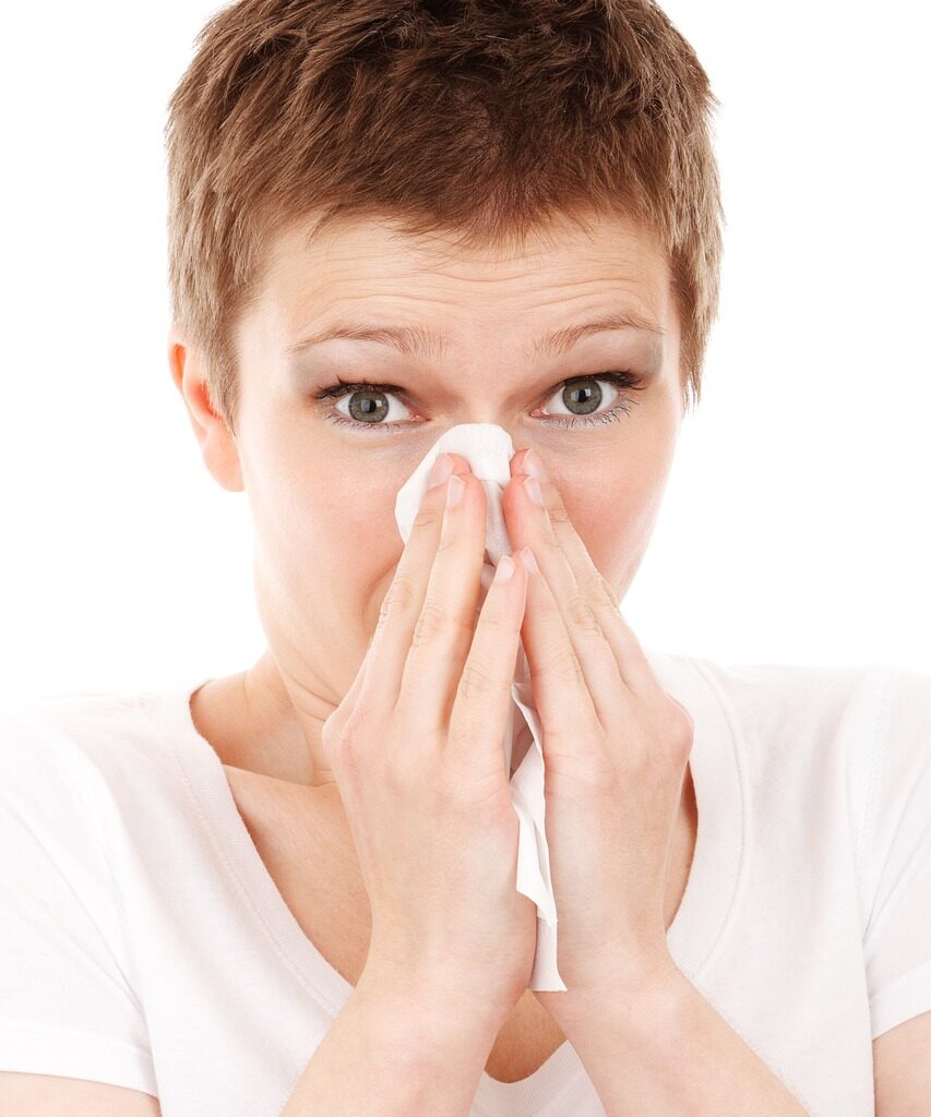 A woman blowing her nose with a tissue.