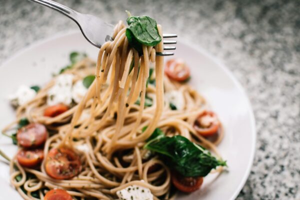 A fork lifted up from a plate of spaghetti