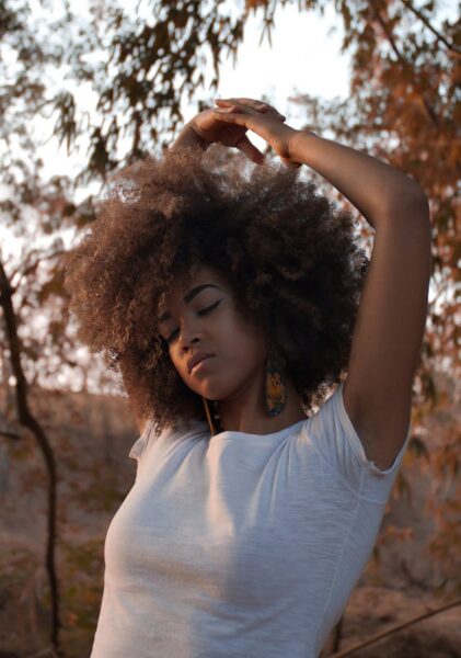 Black woman with type 4 hair posing in front of fall scenery.