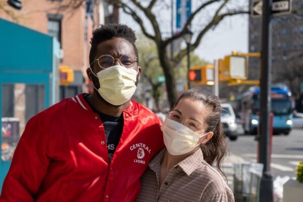 Two masked people hugging