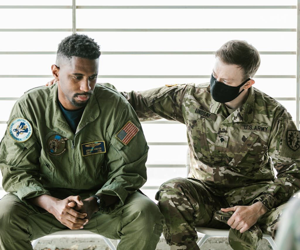 solider supporting other soldier with hand on back in therapy setting