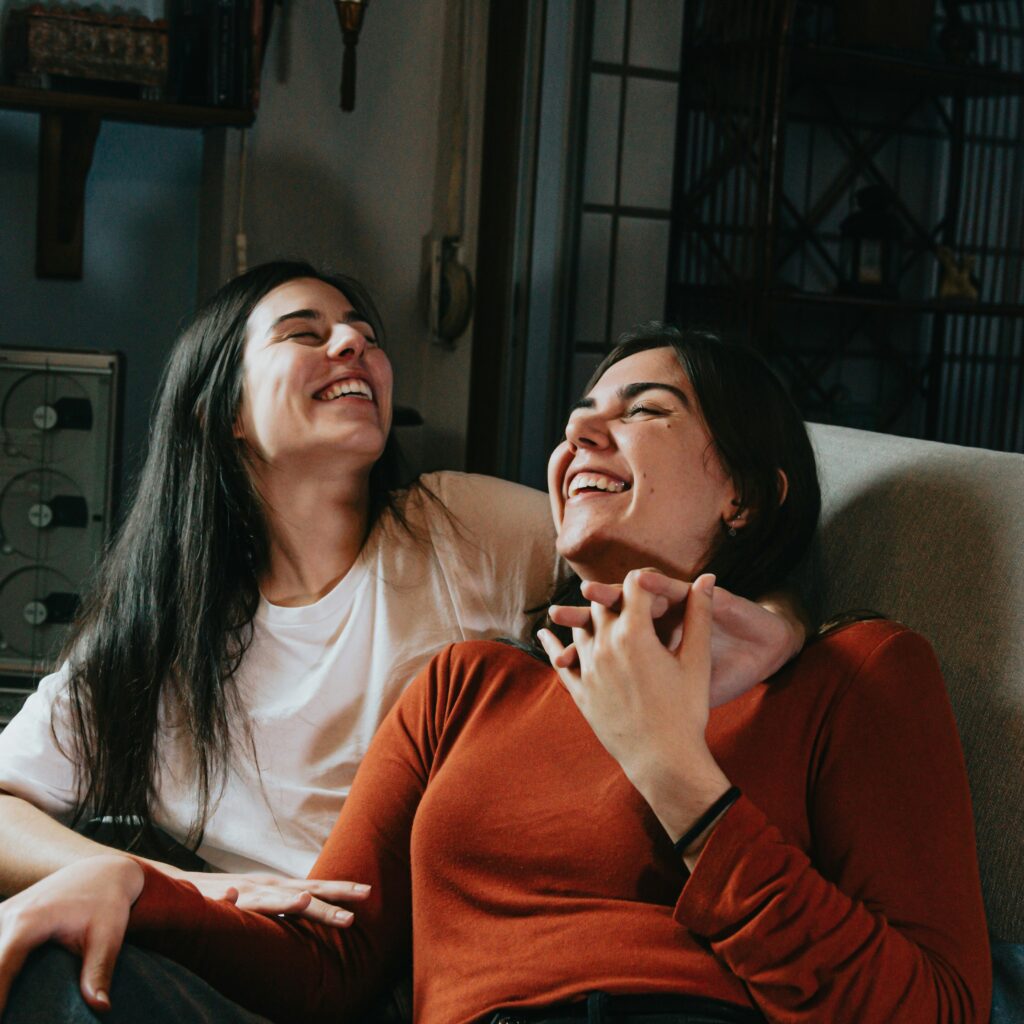 Two women cuddling on the couch. 