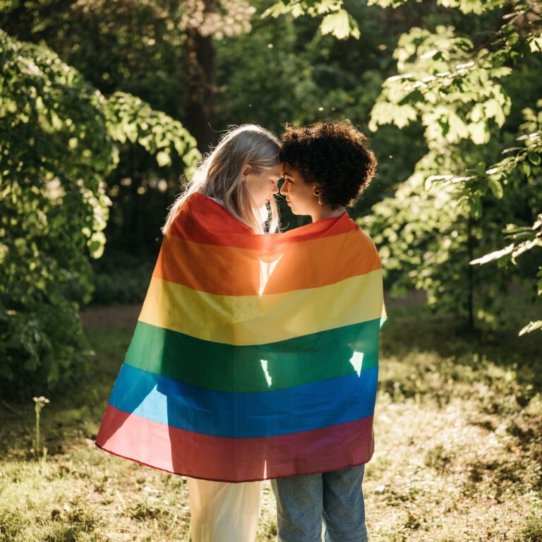 Two women wrapped in the LGBTQ flag
